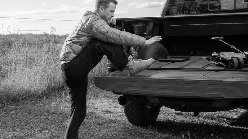 Person struggling with high jump and awkward climb to access pickup truck bed without a step assist.