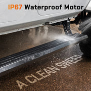 Water splashing onto a Wolfbox electric running board's IP67-rated motor housing, demonstrating all-weather waterproof protection in rain, mud, and off-road conditions.