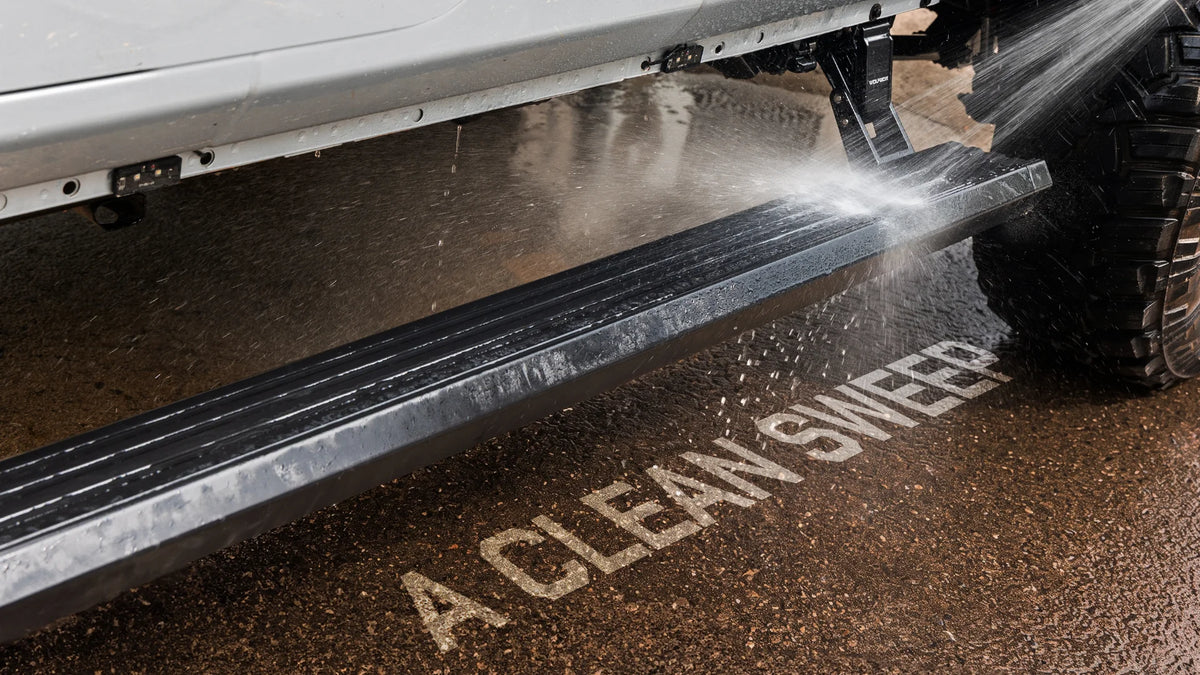Wolfbox power running board being sprayed with water during testing, demonstrating the IP67 sealed motor and housing for rain, mud, and off-road conditions.