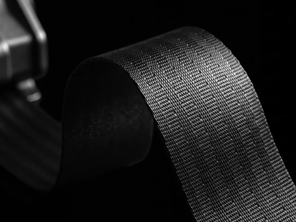 Thick high-tensile polyester webbing on a retractable ratchet strap, woven tight for abrasion resistance and long-lasting strength under heavy loads.