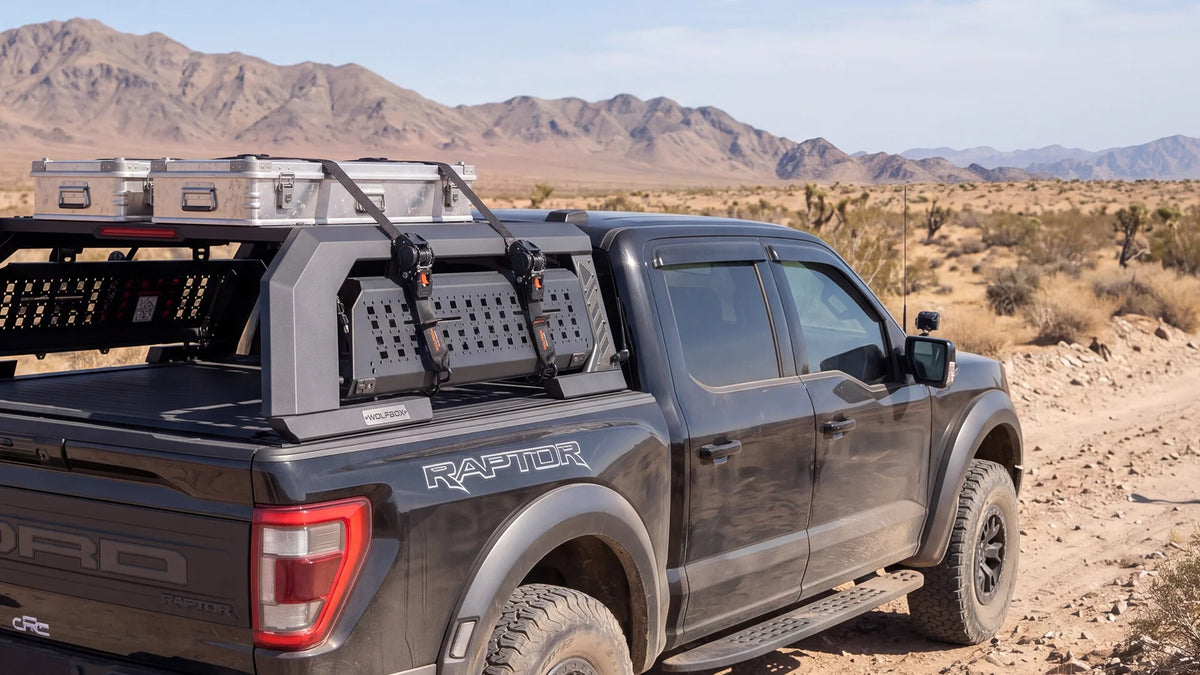 Overland pickup in the desert with roof rack gear secured by retractable ratchet straps, built for long-distance off-road travel and camping.