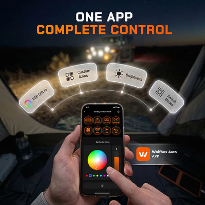 Driver controlling a Wolfbox smart switch panel from a smartphone app in a darkened truck cab, with on-screen sliders for engine start, lights, brightness, and accessories.